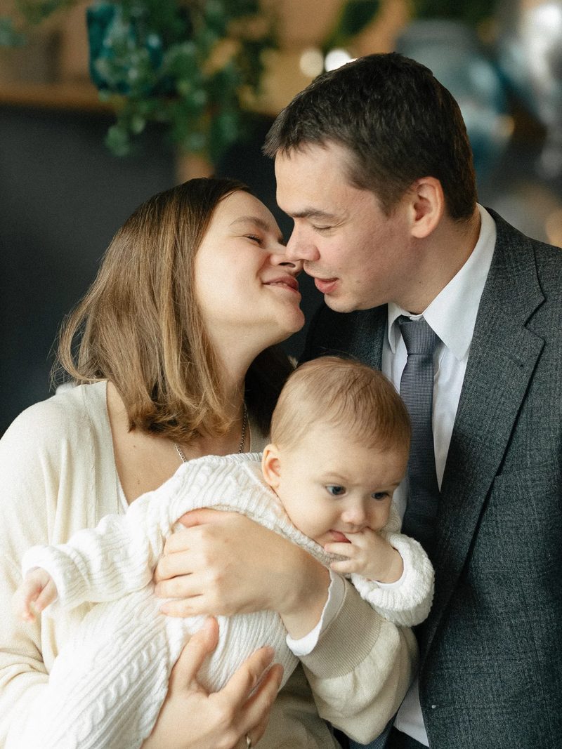 Родители целуются, младенец между ними