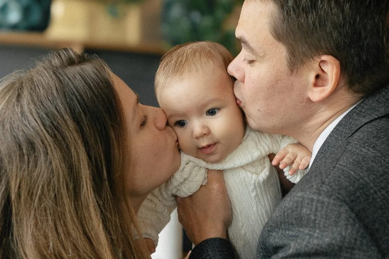 Родители целуют малыша с двух сторон